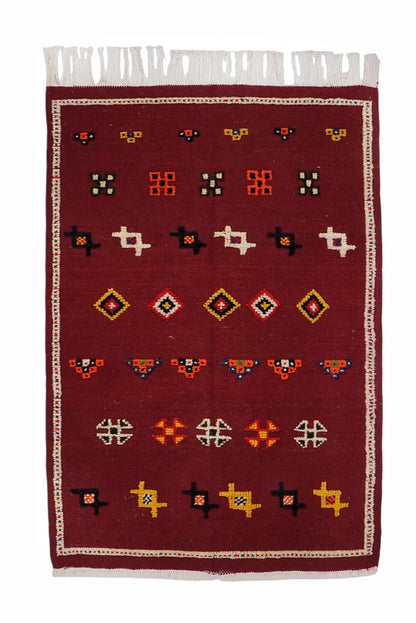 Red patterned rug with white border on a white background