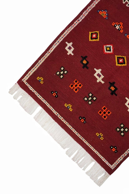 Red patterned rug with white fringe on a white background